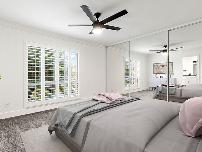 Carpeted bedroom with ceiling fan and large natural light window.. - The Glendon Building