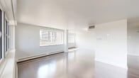 Located on Rue Drummond in the heart of downtown Montréal, this well-appointed 2-bedroom, 3-bathroom residence offers a generous single-floor layout finished with consistent attention to detail throughout. Polished hardwood floors extend across the living areas and bedrooms, reflecting abundant natural light that streams in through large windows framing impressive city skyline views.

The open-concept kitchen and living area serves as the social hub of the residence. The kitchen is fitted with sleek white cabinetry, stone countertops, stainless steel appliances, and a spacious island with an undermount sink — ideal for both everyday living and entertaining. The adjacent living room is bright and expansive, benefiting from multiple large windows.

The primary bedroom is generously proportioned, featuring a door that opens to a balcony with panoramic city views, hardwood flooring, and access to a dedicated walk-in closet with built-in shelving. The second bedroom is equally well-sized and bright.

All three bathrooms are finished in a clean, modern aesthetic. One features patterned floor tiles and a glass-enclosed walk-in shower, while another offers a minimalist design with a floating vanity and tall storage cabinetry. Two hallways provide practical circulation throughout the unit. The overall ambiance is bright, clean, and contemporary.