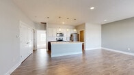 Located at 6770 Printers Blvd in New Albany, Ohio, this well-designed single-floor residence offers 2 bedrooms, 2 bathrooms, and a thoughtful layout that maximizes comfort and functionality. The open-concept kitchen and living area serves as the heart of the home, anchored by a large center island with a sleek countertop and undermount sink. The kitchen features white shaker-style cabinetry, a subway tile backsplash, stainless steel appliances including a refrigerator, range, and built-in microwave, and elegant pendant lighting overhead. Rich wood-style flooring flows throughout the main living spaces, complemented by neutral gray walls that create a clean, contemporary feel. The spacious primary bedroom offers generous proportions, soft carpeting, and multiple windows that invite abundant natural light. It includes a walk-in closet outfitted with wire shelving for organized storage. The second bedroom also features wood-style flooring and a bright window. Both bathrooms are finished with white vanities and wood-style flooring. A dedicated laundry room accommodates a full-size washer and dryer. A bright entryway with recessed lighting and a welcoming front door completes this move-in-ready home.