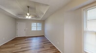 This single-story home is thoughtfully laid out to maximize functionality across its three bedrooms and two bathrooms. The living area is a standout space, featuring a tray ceiling with a ceiling fan, neutral-toned walls, and wood-look hardwood flooring that extends throughout the main living areas. Natural light enters through a front-facing window, creating a bright and welcoming atmosphere. The living area flows openly into a dining space, which is highlighted by an elegant pendant chandelier and textured ceiling.

The bedrooms are finished with plush carpeting, ceiling fans, and windows fitted with blinds, providing comfort and privacy. The spacious primary bedroom offers generous room for furnishings. The bathrooms feature warm wood-toned vanity cabinetry, white countertops, large mirrors, and chrome fixtures. A dedicated laundry area includes upper wood cabinetry for storage and utility hookups. The kitchen features a double-basin sink, light wood cabinetry, and upper storage. Throughout, neutral wall colors and consistent finishes contribute to a clean, cohesive, and move-in-ready aesthetic.