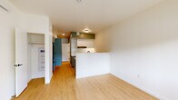 Located at 3260 SE Milwaukie Ave in Portland, Oregon, this efficiently designed single-floor unit makes smart use of its compact footprint. Light wood flooring runs throughout, creating a warm, cohesive aesthetic across every room.

The open living area is bright and airy, anchored by a large picture window that invites natural light and provides views of the surrounding neighborhood streetscape. The clean white walls and recessed lighting enhance the sense of openness.

The kitchen is thoughtfully laid out with sage-green flat-front cabinetry, white square-tile backsplash, light stone countertops, and a matte black faucet over a stainless steel sink. A peninsula separates the kitchen from the living space, adding both function and visual definition. Full-size appliances, including a range with oven and an under-counter refrigerator, are neatly integrated into the cabinetry.

The bathroom is finished to a high standard, featuring floor-to-ceiling vertically laid white tile in a walk-in shower stall with matte black fixtures, including a rain showerhead and hand controls. Matching sage-green cabinetry with black hardware mirrors the kitchen's design language, creating a unified aesthetic throughout the unit. Recessed lighting completes the clean, modern look. A closet with built-in shelving provides additional storage.
