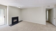 Located at 7843 Roswell Rd in Sandy Springs, GA, this one-bedroom, one-bathroom unit offers a well-organized single-floor layout designed for comfortable everyday living. The combined kitchen and living room serves as the heart of the home, where the living area features plush carpeting, a textured ceiling, and a sleek electric fireplace framed in dark tile — a standout focal point that adds warmth and character. A sliding glass door floods the living space with natural light and provides direct access to a private balcony overlooking lush greenery. The kitchen is equipped with stainless steel appliances, including a refrigerator and dishwasher, complemented by dark granite-style countertops, white cabinetry, and light wood-look flooring. A window with horizontal blinds keeps the kitchen bright and airy. The spacious bedroom offers generous proportions with soft carpeting, neutral walls, a window with garden views, and a closet accessible via a private door. The full bathroom includes a white tiled tub-shower combination, a toilet, and a vanity mirror. A hallway connects the rooms, completing this clean, functional, and move-in-ready layout.