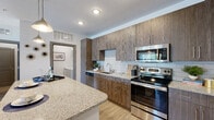Located at 3585 SW 38th Terrace in Ocala, Florida, this thoughtfully designed single-floor residence combines contemporary style with functional living. The open-concept kitchen is a standout feature, showcasing rich wood-toned cabinetry, granite countertops, a classic subway tile backsplash, and a full suite of stainless steel appliances. A large kitchen island with pendant lighting and bar seating makes it ideal for both meal prep and casual dining.

The living area is bright and inviting, with large sliding glass doors dressed in vertical blinds that fill the space with natural light and provide access to an outdoor area with views of the surrounding greenery. The two bedrooms are comfortably sized, each featuring wood-look flooring, ceiling fans, and ample natural light from well-positioned windows. The primary bedroom includes a generous walk-in closet with wire shelving systems offering versatile storage.

The bathroom is clean and modern, with wood-look tile flooring, a granite-topped vanity, and a full soaking tub. A hallway linen closet provides additional built-in storage. Completing this residence is a dedicated in-unit laundry area equipped with a full-size washer and dryer, adding everyday convenience to this well-appointed home.