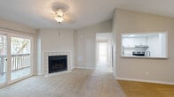 This single-floor residence offers a well-organized layout across two bedrooms, two bathrooms, a combined kitchen and living area, a hallway, and two closets. The living room serves as the focal point of the home, featuring a tile-surround fireplace, neutral carpet flooring, and a ceiling fan with light fixture. A sliding glass door opens directly onto a private balcony with outdoor views of mature trees, filling the space with natural light. Adjacent to the living area, the galley-style kitchen is equipped with stainless steel appliances, white shaker cabinetry, light wood-look flooring, and granite countertops with an undermount sink — offering a clean, functional workspace.

The primary bedroom is a comfortable size, featuring a ceiling fan, a window for natural light, and access to a walk-in closet outfitted with wire shelving systems for organized storage. The second bedroom is similarly appointed with carpet, a ceiling fan, and a window. Both bathrooms are finished with wood-look tile flooring, white vanities, light-toned countertops, and tub-shower combinations. Neutral tones and consistent finishes throughout lend the space a cohesive, move-in-ready aesthetic.