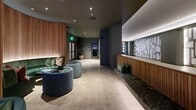 Located at 700 Broadway in Santa Monica, CA, this upscale amenity lounge is a thoughtfully designed, single-floor space that combines social, recreational, and hospitality functions in an expansive, open layout. The space welcomes visitors through a polished reception area featuring warm slatted wood paneling, a dark marble bench with green cushions, and an eye-catching geometric sculptural wall accent that sets a refined tone throughout.

The interior is divided into distinct yet seamlessly connected zones. A lounge area provides plush, curved seating in rich jewel tones — deep greens and blues — arranged around low tables, fostering an inviting atmosphere for relaxed gatherings. A dedicated recreational zone houses a full bowling lane complete with colorful bowling balls, complemented by a large projection screen and a sweeping sculptural LED ceiling light installation that adds dramatic flair.

Adjacent to the bowling area, a billiards room features a full-size pool table alongside a well-appointed bar framed by deep green glazed tile, a mirrored backsplash, and high bar seating — ideal for social entertaining. Throughout the space, large-format light stone flooring, recessed lighting, and dark green wall tones create a cohesive, contemporary aesthetic. Frosted glass exit doors and a tall potted olive tree offer refined finishing touches to this premier amenity destination.