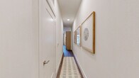 This 1-bedroom, 1-bathroom residence is designed for functional, comfortable living across a single floor. The open-concept kitchen and living area serves as the heart of the home, featuring light wood flat-panel cabinetry that extends floor to ceiling, white quartz countertops, a subway tile backsplash, and a full suite of stainless steel appliances including a refrigerator with ice maker, range, over-the-range microwave, and dishwasher. The living area is bright and inviting, anchored by dark hardwood-style flooring and a ceiling fan, with natural light streaming in through sliding glass doors that open to the outdoors. A narrow hallway connects the main living space to the private areas of the home, adorned with recessed lighting and framed artwork. The generously sized primary bedroom features plush carpeting, a ceiling fan, and direct access to both the bathroom and a dedicated walk-in closet. The walk-in closet offers wrap-around shelving and hanging rods, providing ample storage. The bathroom is finished with warm wood vanity cabinetry and modern fixtures. A stacked washer and dryer unit is also included within the unit, adding everyday convenience. The overall palette is clean and neutral, creating a cohesive and modern living environment throughout.