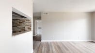 This two-bedroom, one-bathroom single-story unit is located at 8100 Bellaire Blvd in Houston, TX. The layout features two distinct living areas that flow into a dedicated dining space, creating a functional and connected common area. The open layout is anchored by wood-look plank flooring throughout the main living spaces, complemented by neutral gray walls and clean white trim that lend a fresh, modern feel.

The primary living room is highlighted by a white-surround fireplace and a sliding glass door fitted with vertical blinds, allowing for natural light and outdoor access. The kitchen features granite-look countertops and a stacked-stone tile backsplash, adding texture and visual interest. Both bedrooms are carpeted for comfort and include ceiling fans, closets, and windows with blinds that provide natural light and outdoor views.

The bathroom is finished with wood-look vinyl flooring, a gray vanity with granite countertop, a wall-mounted mirror, and a bathtub/shower combination. A dedicated laundry room adds everyday convenience. The unit also includes a hallway that connects the bedroom wing to the main living areas, contributing to a well-organized and practical floor plan throughout.