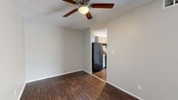 Located at 9805 E 61st St in Raytown, Missouri, this single-floor, one-bedroom, one-bathroom unit offers a practical and comfortable layout across a well-utilized footprint. Dark hardwood-style flooring flows consistently throughout the living areas and bedroom, providing a warm, cohesive aesthetic against neutral gray walls.

The living room is a bright, open space highlighted by a sliding glass door that fills the room with natural light and provides access to an outdoor area with views of surrounding greenery. A ceiling fan adds comfort to the living space, which connects seamlessly to the hallways leading to other rooms.

The kitchen features gray raised-panel cabinetry on both upper and lower levels, white laminate countertops forming an L-shaped workspace, a double-basin stainless steel sink, and space for appliances including a range. A textured ceiling is present throughout the unit.

The bedroom is a well-proportioned room with a window that brings in natural light and recessed lighting overhead. Dark hardwood-style flooring continues here, maintaining design consistency.

The bathroom is finished with tile flooring, a white vanity with cabinet storage, a wall-mounted mirror, and a multi-bulb light fixture, offering a clean and functional space. Two hallways provide efficient circulation throughout the unit.