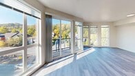 Located along Martin Luther King Jr Way S in Seattle, WA, this well-designed 2-bedroom, 2-bathroom residence offers a thoughtfully organized single-floor layout. Light-toned luxury vinyl plank flooring flows throughout, complementing the clean, modern aesthetic found in every room.

The open-concept living, dining, and kitchen area serves as the heart of the home. The kitchen is appointed with crisp white shaker cabinetry, light countertops, a stainless steel sink, and a full suite of stainless steel appliances including a refrigerator, range, microwave, and dishwasher — all illuminated by recessed ceiling lighting. The living area is a standout, featuring an expansive wall of windows and sliding glass doors that open to a private balcony, flooding the space with natural light and offering pleasant views of the surrounding Seattle neighborhood and tree-lined hillside.

Both bedrooms are comfortably sized with large windows that bring in natural light. The primary bedroom includes closet space and connects easily to the rest of the unit via a bright, clean hallway. The two bathrooms are finished with white vanities, hardware with matte black accents, and wood-look flooring. One bathroom features a full soaking tub and shower combination. A dedicated in-unit laundry area with a stacked washer and dryer adds everyday convenience. Three closets provide ample storage throughout.