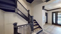 This building's lobby is a striking example of classic architectural craftsmanship, immediately drawing attention with its intricate mosaic tile flooring. The geometric, multi-tone pattern spans the full length of the entryway, adding warmth and visual depth underfoot. Crisp white walls are framed by bold, dark wood crown molding and ornamental corbels, creating a strong contrast that emphasizes the historic character of the space.

A grand staircase with an elegant black-painted wood and metal balustrade anchors one side of the lobby, ascending with a sense of timeless formality. The staircase treads are finished in a complementary stone-like material, reinforcing the refined aesthetic. On the opposite side, a modern elevator provides convenient vertical access, thoughtfully integrated without disrupting the classic ambiance.

The entry vestibule features a traditional multi-pane glass door flanked by sidelights, allowing natural light to filter into the space and creating a welcoming transition from the exterior. Built-in mailbox units are neatly mounted along the walls, offering a functional and well-organized mail center for residents. Globe light fixtures provide soft, even illumination throughout, complementing the historic detailing. Together, these elements create a lobby that is both dignified and highly functional, honoring its architectural heritage while serving the practical needs of daily building life.