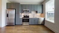 Located at 921 N Central Ave in the heart of Tampa, FL, this single-floor residence offers a thoughtfully designed layout with contemporary finishes throughout. The open living area features warm hardwood-style flooring and a ceiling fan, while large French doors flood the space with natural light and open to a private balcony overlooking the colorful Tampa cityscape — an ideal spot to take in the urban surroundings.

The kitchen is a standout feature, showcasing slate-blue shaker cabinetry accented with brushed gold hardware, white quartz countertops, a classic subway tile backsplash, and a full suite of stainless steel appliances including a refrigerator, electric range, built-in microwave, and dishwasher. Ample upper and lower cabinetry provides generous storage.

The bathroom is equally refined, with dual-tone gray cabinetry, quartz countertops, gold-tone fixtures, a large mirror, and a glass-enclosed tiled shower. Adjacent to the bathroom, a well-organized walk-in closet with built-in shelving offers excellent storage capacity. The bedroom is carpeted for comfort and includes a reach-in closet with wire shelving. Neutral wall tones and clean white trim create a bright, cohesive aesthetic throughout the entire space.
