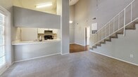 Located at 1409 Tangerine Ct in Arlington, Texas, this two-story home offers two bedrooms and four bathrooms across a well-organized floor plan. The expansive main level serves as the heart of the home, anchored by a dramatic vaulted living room with soaring ceilings that amplify the sense of openness. A stone fireplace with a white-trimmed surround serves as a focal point, flanked by windows that draw in natural light. Neutral carpet and grey-toned walls create a clean, cohesive aesthetic throughout.

The kitchen features a galley-style layout with white cabinetry, black hardware, light countertops, and wood-look flooring. A pass-through counter connects it to the living area, enhancing the open-concept flow. A dedicated laundry closet with hardwood-style flooring and washer/dryer hookups adds practical convenience on the main level.

Upstairs, the generously sized primary bedroom includes plush carpeting, a ceiling fan, and access to a well-appointed suite with mirrored sliding closet doors, built-in shelving, and a tiled tub-shower bathroom. The second bedroom also features carpet, a ceiling fan, and natural light from a large window. Two closets provide ample storage throughout the home.