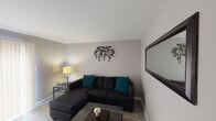 Located at 11420 Knollridge Ln in Cumberland, Indiana, this two-floor home offers a well-organized layout with comfortable living spaces throughout. The living room features neutral gray walls, tile flooring, and a sliding glass door dressed with vertical blinds that allows natural light to fill the room. A large sectional sofa, glass coffee table, and decorative wall art contribute to a relaxed yet stylish atmosphere.

The kitchen is outfitted with white cabinetry, dark granite-style countertops, a stainless steel sink, and a gas range, providing a clean and practical cooking environment. The layout makes efficient use of the available space.

The primary bedroom showcases warm hardwood-style flooring, soft gray walls, a window with views of surrounding greenery, a closet, and ample room for a dresser and shelving. A second bedroom mirrors similar finishes with hardwood-style flooring, a bright window overlooking mature trees, and enough space for comfortable furnishings. A third, smaller bedroom also features hardwood-style floors and a window with outdoor views, making it well-suited as a guest room or home office.

The bathroom is clean and simply appointed with a shower-tub combination and chrome fixtures. Throughout the home, a consistent neutral color palette and natural light from multiple windows create a cohesive and inviting environment.