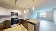 This contemporary one-bedroom apartment at Dominion Middle Ridge offers 760 square feet of thoughtfully designed living space. The open-concept floor plan seamlessly integrates the kitchen, living, and dining areas, creating a spacious and airy atmosphere. The gourmet kitchen boasts a mix of white upper and dark wood lower cabinets, granite countertops, and stainless steel appliances, including a built-in microwave. Pendant lighting adds a touch of elegance to the space.

The generously sized bedroom, measuring 170 square feet, features large windows that flood the room with natural light. A ceiling fan provides comfort and air circulation. The apartment includes a well-appointed bathroom with a combination tub-shower, modern fixtures, and a granite-topped vanity.

Throughout the apartment, light-toned wood-look flooring adds warmth and complements the neutral wall colors. The living area offers ample space for furniture arrangement and includes a built-in heating and cooling unit. A walk-in closet provides generous storage space with customizable shelving.

Large windows in every room ensure abundant natural light and views of the surroundings. The apartment's clean lines, modern fixtures, and neutral color palette create a blank canvas for personalization, making it an ideal space for comfortable and stylish living.