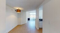 Located at 130 S Alexandria Ave in the Koreatown neighborhood of Los Angeles, this single-floor unit offers a clean, modern aesthetic throughout. Light wood-tone flooring flows seamlessly across all rooms, creating a warm, cohesive feel. The open-concept living and dining area is bright and airy, drawing natural light through sliding glass doors that overlook an outdoor space, while a textured ceiling and a ceiling-mounted light fixture add character.

The kitchen is thoughtfully designed with white shaker cabinetry, grey stone countertops, a peninsula with a modern gooseneck faucet, and a full suite of stainless steel appliances including a gas range, microwave, dishwasher, and refrigerator. Recessed lighting illuminates the workspace effectively.

A hallway connects the private areas of the unit, leading to a spacious bedroom with access to a walk-in closet equipped with built-in shelving and hanging rods — providing generous storage. The primary bathroom features a glass-enclosed shower stall, a stone-topped vanity, and wood-tone flooring. A second bathroom includes a tub-shower combination, a grey-countered double vanity with white cabinetry, and a window for natural light. The layout is practical and well-organized, offering comfort and functionality in the heart of Los Angeles.