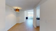 Located at 130 S Alexandria Ave in the Koreatown neighborhood of Los Angeles, this single-floor unit offers a clean, modern aesthetic throughout. Light wood-tone flooring flows seamlessly across all rooms, creating a warm, cohesive feel. The open-concept living and dining area is bright and airy, drawing natural light through sliding glass doors that overlook an outdoor space, while a textured ceiling and a ceiling-mounted light fixture add character.

The kitchen is thoughtfully designed with white shaker cabinetry, grey stone countertops, a peninsula with a modern gooseneck faucet, and a full suite of stainless steel appliances including a gas range, microwave, dishwasher, and refrigerator. Recessed lighting illuminates the workspace effectively.

A hallway connects the private areas of the unit, leading to a spacious bedroom with access to a walk-in closet equipped with built-in shelving and hanging rods — providing generous storage. The primary bathroom features a glass-enclosed shower stall, a stone-topped vanity, and wood-tone flooring. A second bathroom includes a tub-shower combination, a grey-countered double vanity with white cabinetry, and a window for natural light. The layout is practical and well-organized, offering comfort and functionality in the heart of Los Angeles.