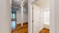 This single-floor loft blends industrial character with modern finishes across a well-organized layout. Rich, rustic hardwood flooring runs throughout the entire space, adding warmth and texture that contrasts beautifully with the crisp white walls and exposed structural elements.

The kitchen is a standout feature, outfitted with a full suite of stainless steel appliances including a refrigerator, electric range with microwave above, and dishwasher. Gray shaker-style cabinetry lines the walls, complemented by a white subway tile backsplash and light stone countertops. A stainless steel prep island anchors the center of the kitchen, adding both functionality and an industrial edge. Exposed ductwork and track lighting overhead reinforce the loft aesthetic.

The open living area is defined by white-painted structural columns and high ceilings, with exposed HVAC ducts and a ceiling fan providing architectural interest and airflow. Natural light filters in through windows, enhancing the airy feel of the space.

The bathroom is clean and modern, featuring a vanity with a granite countertop, an undermount sink, and a full tub-shower combination. The same rustic hardwood flooring continues here, tying the space together cohesively.

Two hallways connect the rooms efficiently, contributing to a logical and functional flow throughout this characterful loft space.