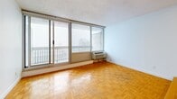Located at 2100 Boulevard De Maisonneuve Ouest in Montreal, this studio unit offers a thoughtfully arranged single-floor layout comprising a living area, kitchen, and bathroom. A narrow entryway corridor with warm parquet flooring guides you into the main living space, where large sliding glass doors flood the room with natural light and provide direct access to an outdoor balcony with open city views. The living area features classic herringbone-patterned parquet flooring throughout, white walls, a textured ceiling, and a raised platform section that adds a subtle architectural dimension to the space. The compact kitchen is efficiently designed with white cabinetry, ample upper and lower storage, white tile backsplash, generous counter space, and stainless steel appliances including a full-sized refrigerator. Light wood-tone flooring completes the kitchen's clean, modern aesthetic. The bathroom is finished with white square wall tiles extending from floor to ceiling, a soaking bathtub with overhead shower, a vanity with storage, and light tile flooring, creating a bright and functional space. The studio's overall design balances practicality with comfort, making it a well-organized unit in the heart of Montreal.