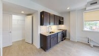Located at 1805 Monument Ave in Richmond, Virginia, this single-floor unit sits along one of the city's most iconic and historically significant boulevards. The interior presents a clean, contemporary aesthetic complemented by light-toned luxury vinyl plank flooring that runs throughout the open layout.

The kitchen serves as a functional centerpiece, outfitted with dark espresso-finish cabinetry, granite-style countertops, and a classic white subway tile backsplash. Stainless steel appliances—including a gas range, built-in microwave, dishwasher, and refrigerator—complete the well-appointed cooking space. Recessed lighting adds a polished finish overhead.

The main living area is open and airy, connecting seamlessly to the kitchen and providing flexible space for a variety of furniture arrangements. Overhead vents indicate a central HVAC system for year-round climate control.

The bedroom offers notable natural light through a trio of windows fitted with neutral roller shades, framing views of the surrounding neighborhood. A tray ceiling detail adds architectural interest to the room.

The bathroom features full subway tile surround in the tub/shower combination, a granite-topped vanity with dark cabinetry, and a large mirror. The cohesive finishes throughout create a unified, modern living environment in a storied Richmond location.