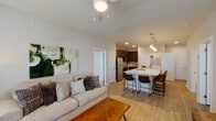 This single-story, two-bedroom, two-bathroom residence offers a thoughtfully designed open-concept layout that seamlessly connects the kitchen, dining, and living areas. Light-toned walls and wood-style plank flooring run throughout, creating a cohesive and contemporary aesthetic.

The kitchen serves as a central hub, anchored by a large white quartz island with an integrated sink, bar seating for multiple guests, and pendant lighting overhead. Dark espresso cabinetry with tile backsplash pairs with stainless steel appliances, including a refrigerator, range, and microwave. A dedicated in-unit laundry area is conveniently located adjacent to the kitchen.

The living room receives generous natural light through large windows dressed with sheer curtains and blinds, and features a ceiling fan. The space is well-proportioned and comfortable.

Both bedrooms are well-sized, each with windows that invite natural light, ceiling fixtures, and wood-style flooring. One bedroom includes a walk-in closet with built-in shelving and hanging rods. The bathrooms maintain the same clean, modern finishes seen throughout the home, including dark cabinetry and light walls, contributing to a consistent and polished overall ambiance.
