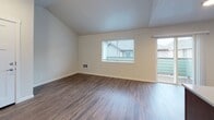 This single-floor residence offers a thoughtfully designed layout that balances open communal spaces with comfortable private areas. The living room makes a strong first impression with its vaulted ceiling, warm dark hardwood-style flooring, neutral wall tones, and a large window paired with a sliding glass door that fills the space with natural light and provides views of the surrounding neighborhood.

The kitchen is a functional and stylish centerpiece, featuring rich dark wood cabinetry, light quartz countertops, a tile backsplash, and a full suite of stainless steel appliances including a refrigerator, range, microwave, and dishwasher. A central island with a matching quartz surface provides additional prep space and casual seating. Pendant lighting adds a refined touch overhead.

The bedrooms are carpeted in a neutral tone, each benefiting from natural light through blinds-equipped windows and offering a clean, versatile canvas. The bathrooms are finished with consistent design elements including dark wood vanities, quartz countertops, tile accents, and brushed gold hardware. A full tub and shower enclosure with built-in shelving is featured in the main bath. Throughout the home, consistent flooring, trim, and neutral color palettes create a cohesive and move-in-ready atmosphere.