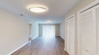 This single-floor residence offers a thoughtfully designed layout that balances open living spaces with comfortable private quarters. The expansive main living area is finished with durable wood-style flooring and neutral warm-toned walls, creating a bright and welcoming atmosphere. Vertical blinds cover a large sliding glass door that fills the room with natural light, while a louvered closet provides convenient storage near the entryway. The kitchen is outfitted with crisp white shaker-style cabinetry, white countertops, a double stainless steel sink, and black appliances including a refrigerator, range, and dishwasher. Track lighting illuminates the workspace, and a window above the sink brings in additional natural light. The bedrooms feature plush carpeting and are generously sized, each benefiting from windows with outdoor views of greenery. One bedroom includes a sliding glass door providing direct outdoor access. The primary bathroom features a full tub and shower combination, while a second bathroom offers a white vanity with an integrated sink and a well-lit mirror. Throughout the residence, clean white trim, neutral tones, and consistent finishes contribute to a cohesive and move-in-ready aesthetic.