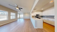 This single-floor, 2-bedroom, 1-bathroom residence offers a thoughtfully designed open-concept layout with consistent light wood flooring running throughout every room. The living and kitchen areas flow seamlessly into one another, creating a bright and cohesive communal space. The living room is generously proportioned, featuring a ceiling fan with a brushed gold finish and multiple windows that invite abundant natural light. The modern kitchen is a standout feature, equipped with crisp white shaker-style cabinetry, a light-toned countertop, a subway tile backsplash in soft gray-blue tones, and a full suite of stainless steel appliances including a side-by-side refrigerator, electric range, and microwave. A kitchen island with pendant lighting adds both functionality and style. The primary bedroom is a comfortable retreat with dual windows, a ceiling fan, and access to a dedicated walk-in closet outfitted with wire shelving for organized storage. The second bedroom mirrors the clean aesthetic, featuring a window and matching flooring. The bathroom is well-finished with white subway tile surrounding the tub-shower combination, a white vanity with brushed nickel hardware, and matching cabinetry above the toilet for added storage. Neutral wall tones and clean finishes contribute to the space's modern, move-in-ready appeal.