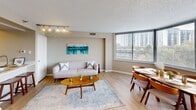 Located at 3001 Park Center Drive in Alexandria, Virginia, this well-appointed one-bedroom, one-bathroom residence offers a thoughtfully designed layout across a single floor. Light wood flooring flows throughout the main living areas, creating a warm and cohesive feel. The combined living and dining area is a standout feature, anchored by expansive floor-to-ceiling windows that frame views of the surrounding Alexandria skyline and treetops, flooding the space with natural light. Track lighting adds an additional layer of ambiance to the living area. The kitchen is outfitted with light wood cabinetry, white quartz countertops, and stainless steel appliances, including an electric range with over-the-range microwave and dishwasher. A hallway connects the main living area to the private quarters. The generously sized bedroom features large windows with city and greenery views, plush carpeting, and ample room for a full furniture arrangement. A well-sized walk-in closet with wire shelving provides substantial storage. The bathroom includes a light wood vanity with a white countertop, a soaking tub, and bright overhead lighting. The overall ambiance is clean, modern, and move-in ready, making this residence a comfortable and functional home in Alexandria.