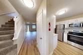 This two-story, two-bedroom, two-bathroom home in Lansing, NY offers a thoughtfully designed layout spread evenly across two floors. The main level features an open-concept kitchen and living area, a separate dining room, and a patio for outdoor enjoyment. The kitchen is well-appointed with white shaker-style cabinetry, light quartz countertops, stainless steel appliances including a refrigerator, range, microwave, and dishwasher, and durable hardwood-style flooring that extends throughout the main living spaces. A hallway connects the main areas, complemented by a staircase with classic white balusters leading to the upper floor. The bathrooms feature elegant hexagonal tile flooring, dark-finish vanities with white countertops, and a tub-shower combination. Both bedrooms are generously sized, with the primary bedroom offering plush carpeting and ample closet space. The second bedroom also features hardwood-style flooring and natural light from a window. With four closets total, storage is plentiful throughout the home. Neutral tones and clean finishes create a bright, move-in-ready atmosphere, while the surrounding green lawn adds a welcoming outdoor setting.