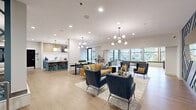 Located at 450 Warrenville Rd in Lisle, IL, this generously sized single-floor amenity space offers a thoughtfully designed environment built for comfort, community, and productivity. The welcoming entry features large-format tile flooring, clean white walls, and a built-in service counter accented by natural stone tile, setting a polished tone from the moment of arrival. A curved hallway adorned with a striking wood sculptural art installation guides visitors deeper into the space. The expansive open lounge area serves as the heart of the floor, combining warm hardwood-style flooring with a sophisticated mix of seating arrangements — from mustard yellow sofas and navy accent chairs to mid-century-inspired armchairs — all illuminated by decorative globe and multi-arm chandeliers. Floor-to-ceiling windows flood the area with natural light and offer lush outdoor views. A kitchen-style bar with teal cabinetry, quartz countertops, and pendant lighting provides a social gathering spot alongside communal dining and high-top seating. A dedicated lounge nook features a teal geometric accent wall and mounted TV. The well-equipped fitness center, visible in the floorplan, offers a comprehensive range of exercise equipment. Private meeting rooms with carpeted floors, track lighting, and curated artwork complete the offering, making this a versatile and refined amenity destination.