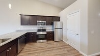Located at 3062 12th Ave SE in Hickory, NC, this single-story, 2-bedroom, 2-bathroom home offers a well-designed layout with modern finishes throughout. The open-concept kitchen and living area serves as the heart of the home, featuring vaulted ceilings, wood-look LVP flooring, and a ceiling fan that enhances the airy feel of the space. The kitchen is equipped with dark espresso cabinetry, granite-style countertops, stainless steel appliances including a refrigerator, range, and over-the-range microwave, and flows seamlessly into the living area. A door off the living room provides convenient exterior access. Both bedrooms are carpeted and include ceiling fans and window blinds, with the primary bedroom offering two windows for added natural light. The two bathrooms share a consistent design aesthetic, featuring dark vanity cabinetry with granite-style countertops and LVP flooring; one bathroom includes a shower-tub combination. The attached garage is spacious, equipped with an automatic opener, recessed lighting, and a windowed door. Neutral wall tones and clean finishes create a cohesive, move-in-ready atmosphere throughout the home.