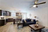 Located at 9103 Gabbro Lane in Boiling Springs, SC, this two-story home offers a well-designed layout spread across two generous floors, plus a basement level. The main floor centers around an open-concept kitchen and living area, where rich dark-stained wood cabinetry, light granite countertops, and stainless steel appliances make the kitchen both functional and visually striking. Pendant lighting and recessed fixtures add warmth, while light hardwood-style flooring flows seamlessly into the living room. The living area is bright and comfortable, anchored by a ceiling fan and natural light from multiple windows. Two bedrooms are thoughtfully sized, each featuring ceiling fans, hardwood-style flooring, and natural light. The primary bedroom includes a dedicated walk-in closet with built-in wire shelving. The two bathrooms are clean and modern, with one featuring a soaking tub, wood-tone vanity, and white countertop. The basement level is a standout feature, offering an expansive unfinished space with concrete block walls, a polished concrete floor, and two garage doors — ideal for vehicle storage, a workshop, or future finishing. This home combines practical storage solutions with comfortable, move-in-ready living spaces.