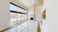 Located in the desirable Silver Lake neighborhood of Los Angeles, this two-story home offers six bedrooms and five bathrooms across a generously sized layout spread over two floors. The main level impresses immediately with a grand living room boasting soaring ceilings and a wall of large, grid-paned windows that flood the space with abundant natural light. Polished marble-style tile floors reflect the sunlight beautifully, and a striking floor-to-ceiling marble fireplace serves as the room's dramatic focal point. Adjacent to the living area, the kitchen features white shaker cabinetry, granite countertops with a bold veined backsplash, and stainless steel hardware. The bathrooms are finished with marble-look tile flooring, white vanities with granite countertops, and clean, bright fixtures. Bedrooms are well-proportioned and bright, with warm wood-look flooring, natural light from grid-paned windows, and select rooms featuring sliding mirrored closet doors. The upper floor hosts additional bedrooms and bathrooms connected by hallways with modern open-railed staircases. Throughout the home, a consistent palette of crisp whites and warm wood tones creates a clean, contemporary aesthetic suited for comfortable multi-room living in Los Angeles.