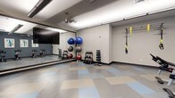 This fitness room is thoughtfully designed to accommodate a wide range of exercise activities. The space features a clean, open layout with a patterned tile floor in soft blue, beige, and gray tones, providing a durable and easy-to-maintain workout surface. A large mirrored wall spans one side of the room, enhancing the sense of space while allowing users to monitor their form during exercise. The room is outfitted with a variety of equipment, including multiple dumbbell racks with graduated weights, a collection of stability balls in assorted sizes, and a TRX suspension training system mounted to the wall. A ceiling fan ensures comfortable air circulation throughout the space. Recessed and track lighting provide bright, even illumination across the entire room. The neutral-toned walls and organized equipment layout give the space a clean, professional atmosphere. The open floor area allows for stretching, bodyweight exercises, and functional fitness movements. Overall, this fitness room is a practical and versatile space well-suited for both individual strength training and group workout sessions.