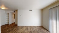 This single-floor unit offers a practical and comfortable layout with a clean, neutral aesthetic throughout. The main living area features warm wood-look laminate flooring and crisp white walls, creating a bright and open atmosphere. A pass-through window connects the living space to the kitchen, enhancing the sense of openness between rooms. The front entryway leads directly into the living area, providing a welcoming and straightforward flow.

The kitchen is well-equipped with warm honey-toned cabinetry extending to the ceiling for ample storage, dark granite-style countertops, a built-in range, and a full-size black refrigerator. A window above the sink allows for natural light to fill the space. The flooring continues the wood-look laminate found throughout the main areas.

The bedrooms are carpeted for added comfort and feature neutral walls and windows fitted with blinds that allow for natural light control. One bedroom includes a built-in closet with louvered sliding doors and dedicated shelving and hanging space.

The bathroom is neatly appointed with a wood-vanity cabinet, dark granite-style countertop, a large mirror with overhead lighting, and a tub-shower combination. Wood-look flooring carries through this space as well, maintaining a cohesive look throughout the unit.