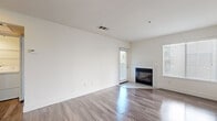 Located at 2991 College Ave in Livermore, CA, this single-level, one-bedroom, one-bathroom unit offers a clean and functional layout designed for comfortable everyday living. The open-concept living and dining area is a standout feature, showcasing gleaming wood-style flooring throughout, crisp white walls, and abundant natural light streaming in through multiple windows dressed with horizontal blinds. A corner fireplace with a sleek black surround serves as a focal point, adding warmth and character to the living space. The kitchen is accessible via a pass-through counter and is equipped with white cabinetry, a stainless sink, a dishwasher, and a black refrigerator — all finished with the same wood-style flooring for a cohesive aesthetic. The bedroom is a well-proportioned, light-filled room with a window offering views of surrounding greenery and direct access to a dedicated walk-in closet outfitted with wire shelving for organized storage. The full bathroom features a wide vanity with white cabinetry, a large mirror, and a full tub-shower combination with a window above for natural ventilation. Throughout the unit, the neutral color palette and consistent flooring create a bright, clean, and move-in ready environment.