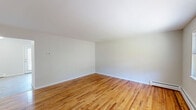 Located at 90 Stonefield Dr in Waterbury, Connecticut, this two-story home offers three bedrooms and one bathroom across a well-organized floor plan. The main level hosts the living room, kitchen, and key living areas, while the upper level accommodates the bedrooms and bathroom, connected by a central staircase. Warm-toned hardwood flooring runs throughout the living areas and bedrooms on both floors, lending a consistent and inviting character to the home. The living room is bright and open, with clean white walls and natural light flowing in through the windows. The kitchen features white shaker-style cabinetry, dark granite-look countertops, tile flooring, and white appliances including a range and refrigerator, along with a pantry closet and a glass-panel exterior door that opens to outdoor views. The spacious primary bedroom includes two windows with outdoor views and a baseboard heating unit. All bedrooms are fitted with closets, including bifold-door designs, providing ample storage. The bathroom is clean and functional, featuring a full tub-shower combination with white tile surround. Throughout the home, baseboard heating is present, and the neutral color palette creates a calm, move-in-ready environment.