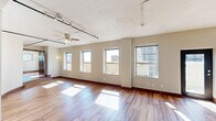 Located in the heart of downtown Dallas at 1501 Main St, this loft-style unit offers a distinctive urban living experience defined by open layouts, rich hardwood flooring, and generous natural light throughout. The elongated floor plan encompasses three living areas, each bathed in sunlight streaming through large windows that frame views of the surrounding Dallas cityscape. Ceiling fans are featured throughout, adding both function and character.

The kitchen is sleek and well-appointed, featuring dark cabinetry, white tile backsplash, stainless steel appliances including a refrigerator, microwave, and range, along with pendant and track lighting that illuminate the space stylishly. An adjacent glass door leads to additional outdoor access, enhancing the flow of the unit.

Two bathrooms serve the space, one offering a glass-enclosed walk-in shower with subway tile surround and brushed nickel fixtures, and another featuring wood-toned cabinetry, a white countertop vanity with mirror, and hardwood flooring. Exposed ductwork in the bathrooms adds to the loft aesthetic.

A dedicated laundry room provides full-size washer and dryer units alongside built-in wire shelving for storage. A closet with sliding mirrored doors offers additional organization. Track lighting and ceiling fans throughout complete this well-designed urban retreat.