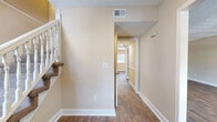 Located in Atlanta, GA, this two-story home offers 4 bedrooms and 5 bathrooms thoughtfully distributed across two well-proportioned floors. The main level features a combined kitchen and living area anchored by a richly appointed kitchen with deep cherry wood cabinetry, granite-style countertops, a tile mosaic backsplash, and black appliances. Natural light pours in through multiple windows, complementing the warm hardwood-style flooring found throughout the main living spaces. The living and dining areas are finished with elegant pendant lighting and crown molding details, creating a welcoming ambiance. A dedicated utility room and hallways with clean white trim add to the functional layout of the first floor. Upstairs, the four bedrooms are carpeted for comfort, each offering natural light through window treatments. The spacious primary bedroom includes a ceiling fan, crown molding, and access to a well-appointed bathroom featuring rich cherry wood vanity cabinetry with granite-style countertops and a separate tub and shower area. Multiple closets throughout the home, including walk-in configurations with built-in shelving, provide generous storage. A carpeted staircase with a classic white balustrade connects both levels, tying together a cohesive and practical residential design.
