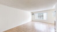 Located at 9150 Tampa Ave in the Northridge neighborhood of Los Angeles, Unit 217 is a thoughtfully arranged single-floor residence that maximizes its compact footprint. The unit features light wood-style flooring throughout, creating a cohesive and clean aesthetic across all areas.

The living room is bright and open, featuring a large window with horizontal blinds that allows natural light to fill the space. A wall-mounted air conditioning unit provides climate control, and a textured popcorn ceiling adds a classic touch. The open layout offers flexibility for various furniture arrangements.

The kitchen is efficiently designed with white shaker-style cabinetry, dark granite countertops, a stainless steel refrigerator, and a built-in stove. A window over the counter area brings in additional natural light, making the space feel airy. Under-cabinet lighting and a stainless steel sink complete the functional setup.

The bathroom features white cabinetry with sleek brushed nickel hardware, a dark granite vanity countertop with a vessel-style sink, a large mirror, and a bathtub. A tall storage cabinet provides ample organizational space.

Two closets offer practical storage solutions throughout the unit. The overall palette of white walls, light flooring, and modern fixtures creates a clean, neutral environment well-suited for comfortable urban living.