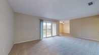 This single-floor residence offers a thoughtfully laid-out interior finished in warm, neutral tones throughout. The spacious living area is anchored by plush carpeting and features a sliding glass door that opens directly onto a private balcony, allowing natural light to pour in and providing pleasant outdoor views. A ceiling fan overhead adds functional comfort to the adjoining area, which transitions seamlessly via light wood-look flooring into the rest of the unit. The kitchen is well-appointed with crisp white shaker-style cabinetry, light countertops, a tile backsplash, and black Whirlpool appliances including a range and over-the-range microwave. Wood-look vinyl flooring runs throughout the kitchen, lending a clean, modern aesthetic. Multiple bedrooms offer generous proportions, each carpeted and painted in soft beige tones, with windows that bring in natural light. The bathroom is finished with wood-look vinyl flooring, a white vanity, and a full tub-shower combination with white tile surround and chrome fixtures. Clean white trim and baseboards frame every room, creating a cohesive and well-maintained living environment throughout this inviting single-level home.