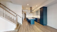 This well-designed two-story home offers a thoughtful layout across both levels, combining modern finishes with functional living spaces. The centerpiece of the main floor is a striking kitchen that immediately commands attention. Bold navy lower cabinetry pairs elegantly with crisp white upper cabinets, while a herringbone tile backsplash, stone countertops, and brushed gold fixtures add refined detail. A central island provides additional prep and gathering space, and a stainless steel range hood and built-in appliances complete the chef-ready setup. Wide-plank wood-look flooring flows seamlessly from the kitchen into the open living area, which benefits from multiple windows that invite natural light and offer views of the surrounding neighborhood. A staircase with a classic wood railing connects the main floor to the upper level. Upstairs, carpeted bedrooms offer a quieter, comfortable retreat, each with windows providing natural light. The upper hallway, finished with wood-look flooring, leads to the bedrooms and connects to well-appointed shared spaces. A dedicated laundry area with a front-load washer adds everyday convenience. Clean white walls, recessed lighting, and consistent trim work throughout give the home a cohesive, modern aesthetic from top to bottom.