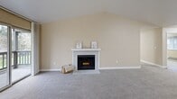 Located at 3120 NE John Olsen Ave in Hillsboro, Oregon, this single-floor, 3-bedroom, 2-bathroom home offers a well-organized layout with a warm, neutral color palette throughout. The entrance leads into a hallway that opens to a combined dining and living area, where vaulted ceilings create a sense of spacious volume. A tile-surround fireplace serves as the focal point of the living room, complemented by plush carpeting and a sliding glass door that provides access to a private balcony with greenery views. The kitchen features light wood cabinetry, stainless steel appliances including a range and refrigerator, a dishwasher, and durable wood-look flooring, with a window that brings in natural light. The generously sized primary bedroom includes vaulted ceilings and dedicated closet space. Two additional bedrooms offer carpeted flooring, windows with outdoor views, and baseboard heating. Both bathrooms are finished with wide vanities, light countertops, wood-trimmed cabinetry, and mirror lighting. Four closets throughout the home provide ample storage. A dedicated laundry area and four closets add to the home's practicality. The overall ambiance is bright, clean, and functional, suited for comfortable everyday living.