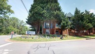 Barclay Place is a well-established residential community that combines classic architectural design with a lush, natural environment. The exterior of the building showcases traditional red brick construction accented by navy blue siding details, lending the property a timeless and appealing aesthetic. Mature evergreen trees tower over the grounds, providing generous shade and a sense of privacy while contributing to the community's serene, park-like atmosphere.

The multi-story structure features private balconies, offering residents outdoor space with pleasant views of the surrounding greenery. The landscaped grounds are thoughtfully maintained, with layered plantings and natural stone accents that enhance the property's curb appeal and create an inviting arrival experience.

Barclay Place is prominently identified by a clean, modern community sign at the entrance, reflecting a well-managed and community-oriented environment. The single-floor layout featured within the space provides a straightforward, accessible flow, making it practical and comfortable for everyday living. Overall, Barclay Place offers a harmonious blend of classic residential character, mature natural surroundings, and a welcoming community atmosphere that makes it a distinctive and desirable address.