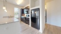 Located in the South Junction neighborhood of Memphis, Tennessee, this single-story residence features a clean, modern design with light wood-style flooring flowing consistently throughout every room, creating a cohesive and airy atmosphere.

The open-concept living and kitchen area forms the heart of the unit. The kitchen is well-appointed with dark espresso cabinetry, granite-style countertops, a full suite of black appliances including a refrigerator, range, and built-in microwave, and a peninsula with pendant lighting overhead. Natural light enters through multiple windows, brightening the adjoining living area, which offers generous open space and an unobstructed layout.

The bedroom is comfortably sized, featuring a ceiling fan, multiple windows with blinds, and direct access to a spacious walk-in closet outfitted with wire shelving along multiple walls for ample storage.

The bathroom includes a dark-cabineted vanity with an undermount sink, a full tub and shower combination with a curved curtain rod, and matching flooring that ties the room together.

A dedicated laundry area houses a full-size washer and dryer, adding everyday convenience. The overall design is neutral and well-maintained, presenting a functional and inviting living environment.