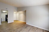Located at 5130 E Ponce de Leon Ave in Tucker, GA, this one-bedroom, one-bathroom unit offers a well-organized and functional layout across a single floor. The living room is a welcoming space featuring wood-style hardwood flooring, neutral gray walls, and a large window that fills the room with natural light and offers views of the surrounding greenery. A pass-through counter connects the living area to the galley-style kitchen, which is equipped with dark espresso cabinetry, light speckled countertops, black appliances including an electric range and refrigerator, and a stainless steel sink — all designed for efficient use of space. The bedroom is a comfortable retreat with plush carpeting, a sizable window with blinds, and direct access to a walk-in closet outfitted with multiple hanging rods and shelving for generous storage. The bathroom includes a vanity with dark cabinetry and a light countertop, alongside a tiled shower-tub combination. The entryway, accented by a track light fixture and wood-style flooring, provides a clean and inviting transition into the home. Neutral tones and consistent finishes throughout give the unit a cohesive, move-in-ready feel.