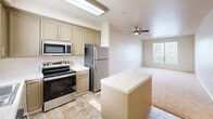 Located at 24 S El Camino Real in Greenfield, CA, this single-floor, 2-bedroom, 1-bathroom residence offers a functional and comfortable layout. The kitchen is well-appointed with taupe cabinetry, stainless steel appliances including a refrigerator, electric range, built-in microwave, and dishwasher, complemented by a tile countertop center island and warm stone-look tile flooring. A skylight fixture brightens the workspace, and a window above the sink adds natural light. The kitchen opens seamlessly into the combined dining and living area, which features plush carpeting, a ceiling fan, and a window that allows natural light to fill the space. Both bedrooms are carpeted and finished with neutral tones, each offering windows with blinds. The primary bedroom includes a generous sliding double-door closet, providing ample storage. Three closets in total are distributed throughout the unit. The hallway connects the living spaces to the bathroom, which features a vanity with cabinetry, a large mirror, a lighted fixture, and stone-look tile flooring consistent with the kitchen. The overall aesthetic is clean and neutral, with warm beige tones throughout, creating a cohesive and move-in-ready living environment.