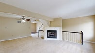Located at 4000 Wellington Drive in Oakdale, PA, this three-floor townhome offers 3 bedrooms and 4 bathrooms across a well-organized layout. The entry-level garage features built-in storage space beneath the staircase and a sectional overhead door. The main living floor serves as the heart of the home, combining the kitchen and living room in an open-plan arrangement. The kitchen is equipped with dark espresso cabinetry, stainless steel appliances including a range, microwave, and dishwasher, and light stone-look countertops over wood-look flooring. The adjacent living room is generously sized, highlighted by a white-mantled fireplace, plush carpeting, a ceiling fan, and a trio of windows that bring in natural light. Carpeted stairs with white balusters and a dark handrail connect all three levels. The upper floor houses all three bedrooms, each featuring neutral tones, carpet flooring, and closets with panel doors. One bedroom includes a window with an outdoor view. The bathrooms are cleanly finished, with one featuring a soaking tub framed by tiled surround and a distinctive octagonal window. A utility room and two hallways round out the practical layout of this well-structured home.