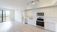 This contemporary 870 square foot apartment, located at Beacon - N707, offers a well-designed living space with two bedrooms and two bathrooms. The open floor plan maximizes the use of space, creating a seamless flow between rooms. The kitchen is a highlight, featuring sleek white cabinetry, stainless steel appliances, and a spacious refrigerator with water dispenser. Light wood-look flooring runs throughout, complementing the crisp white walls and lending a bright, airy feel to the space.

Both bedrooms are generously sized, with the primary bedroom measuring 140 square feet. Large windows in the bedrooms provide ample natural light and scenic views. The bathrooms are modern and well-appointed, with one featuring a glass-enclosed shower, stylish tile work, and a floating vanity. 

Storage is abundant, with walk-in closets in the bedrooms and additional closet space in the hallway. The apartment also includes a ceiling fan for improved air circulation and comfort. The overall design emphasizes clean lines and a neutral color palette, creating a versatile canvas for various decorating styles. This apartment combines functionality with contemporary aesthetics, offering a comfortable and stylish urban living experience.