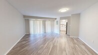 Located at 5 Stonewain Ct in Towson, MD, this well-appointed two-bedroom, two-bathroom single-floor home offers a clean, modern aesthetic throughout. The open living room is a standout space, featuring light wood-style flooring and a wide sliding glass door dressed with vertical blinds that floods the room with natural light and provides outdoor access. The layout flows directly into the kitchen, which has been tastefully updated with white shaker-style cabinetry, granite countertops, a classic subway tile backsplash, and stainless steel appliances including a dishwasher and gas range. A central hallway connects the main living areas to the bedrooms, bathrooms, and laundry, with light wood-style flooring continuing throughout. The primary bedroom is generously sized, offering plush carpeting, a sliding glass door with outdoor views, and a closet. The second bedroom also features wood-style flooring and ample space. Both bathrooms are finished with white cabinetry, granite countertops, and tub-shower combinations. Three closets provide excellent storage throughout. The neutral color palette and consistent finishes lend the home a cohesive, move-in-ready feel.